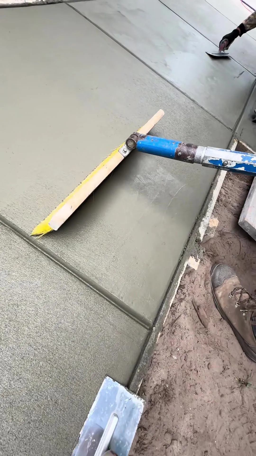 Crew running a finishing pass across a fresh poured concrete slab