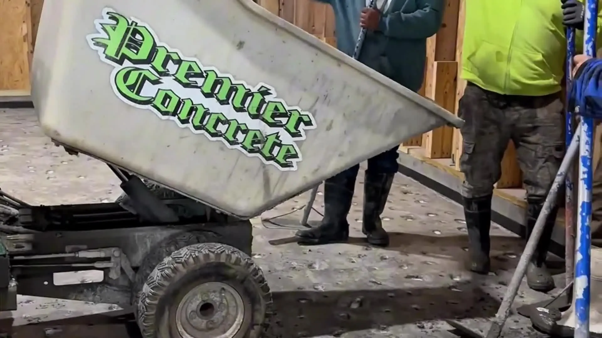 The green Old-English Premier Concrete wordmark on the crew's power buggy