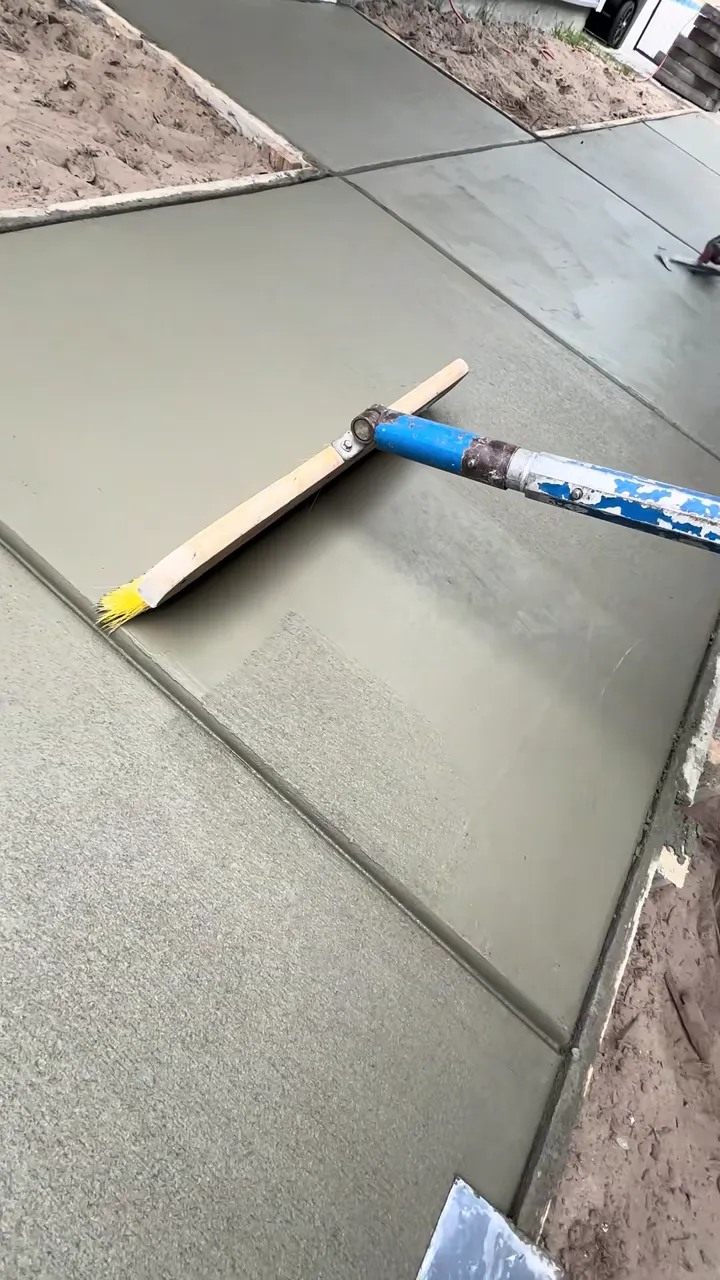 A bull float running a finishing pass across a fresh poured concrete slab