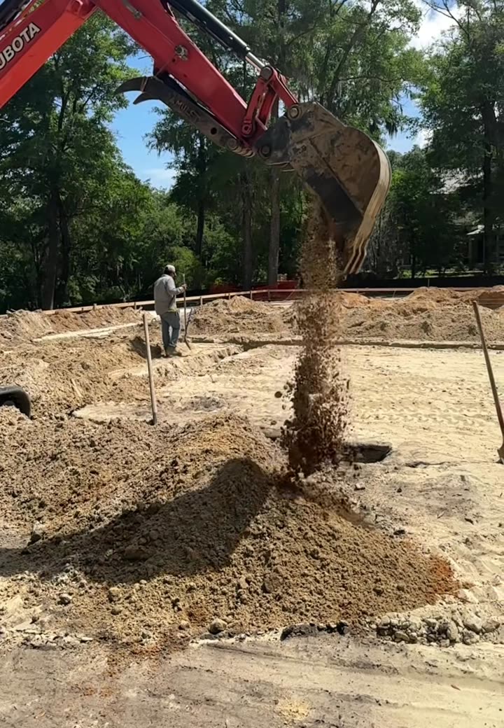 Compact excavator grading and prepping a building site before the pour